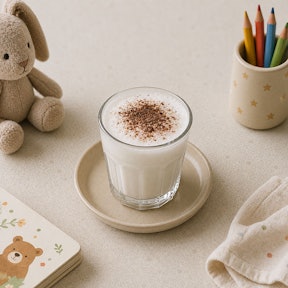 Babyccino van opgeschuimde melk met cacaopoeder erop