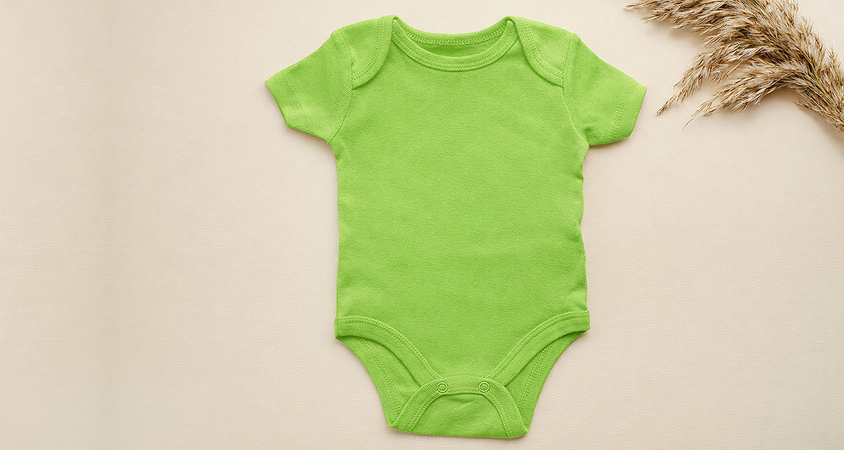 Groene baby romper op houten ondergrond als voorbeeld voor het downloadbare babykleding wasprogramma