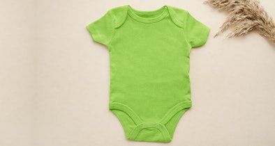 Groene baby romper op houten ondergrond als voorbeeld voor het downloadbare babykleding wasprogramma