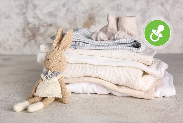 Opgevouwen babykleding met zachte stoffen en knuffel