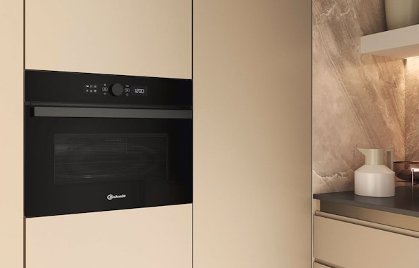 Bauknecht inbouw combimagnetron met zwarte glasdeur in een moderne lichte keuken