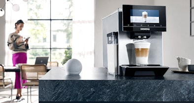 Vrouw die een Siemens volautomatische koffiemachine bedient via de app op haar telefoon