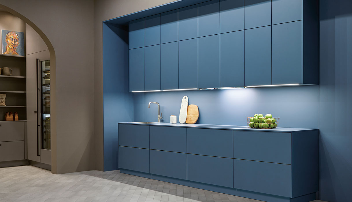 Moderne blauwe keuken met greeploze kasten, geïntegreerde verlichting en minimalistisch werkblad.