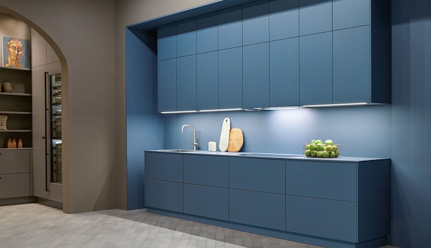 Moderne blauwe keuken met greeploze kasten, geïntegreerde verlichting en minimalistisch werkblad.