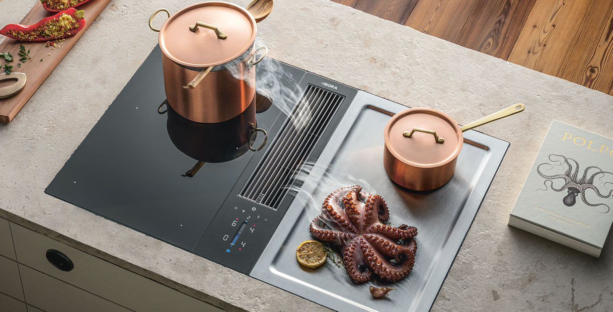 BORA Classic 2.0 kookplaat met afzuiging en twee koperen pannen op inductieveld naast houten snijplank