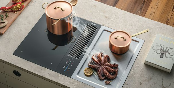 BORA Classic 2.0 kookplaat met afzuiging en twee koperen pannen op inductieveld naast houten snijplank