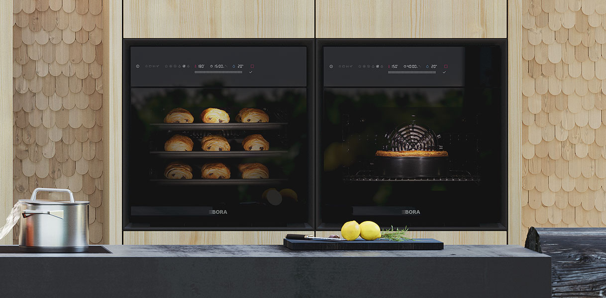 Twee BORA stoomovens naast elkaar, links met gebak op drie niveaus en rechts met een ovenschaal