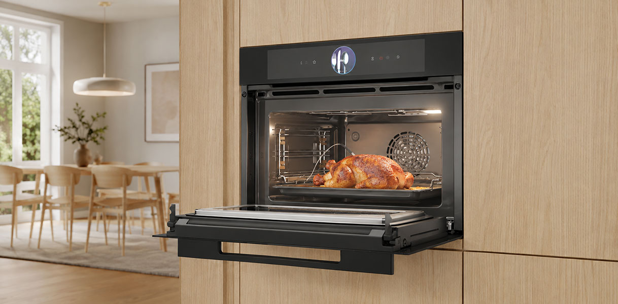 Bosch combimagnetron met geopende deur en gebraden kip in een licht eiken keuken.