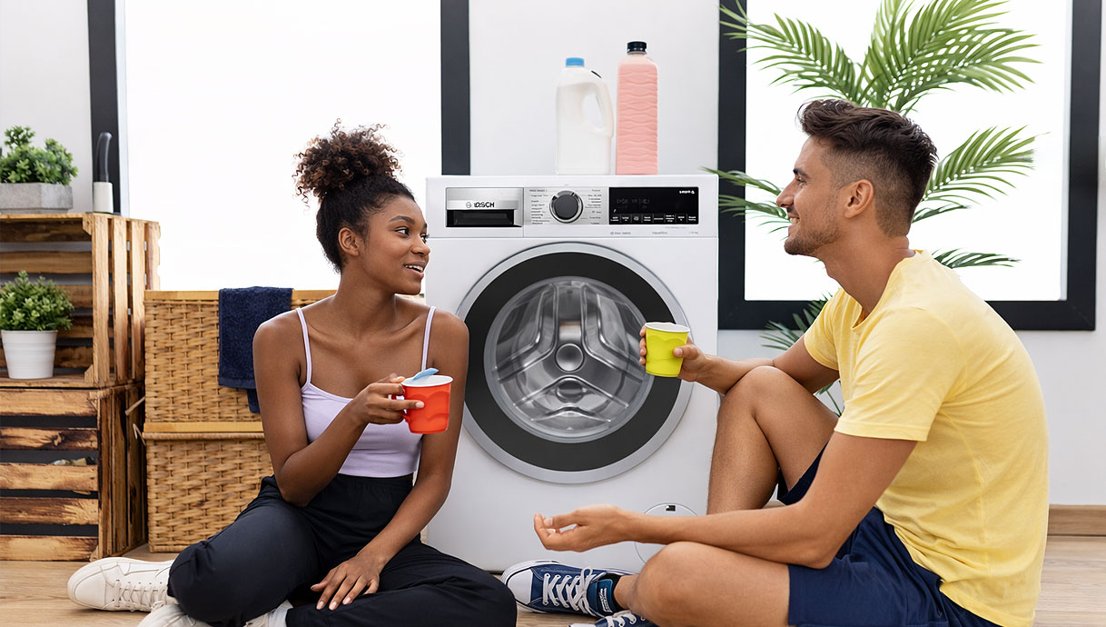 Bosch wasmachine in moderne woonomgeving met twee personen die ontspannen naast de machine zitten