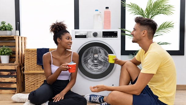 Bosch wasmachine in moderne woonomgeving met twee personen die ontspannen naast de machine zitten