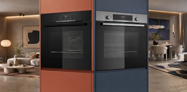 Zwarte Bosch oven naast een model met roestvrijstalen accenten ingebouwd in de keuken