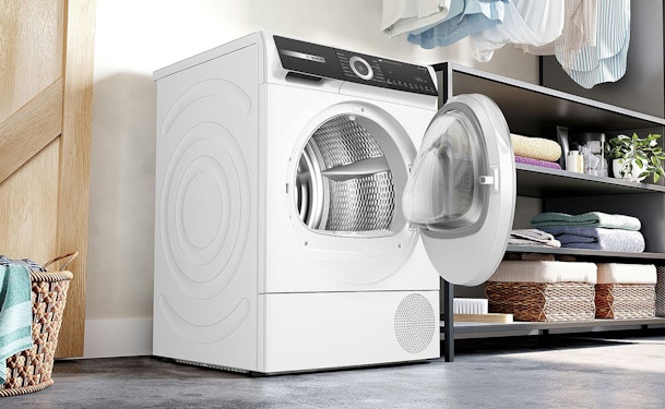 Bosch warmtepompdroger met open deur naast wasmachine in moderne wasruimte