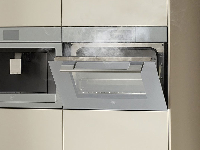 V-ZUG combi-stoomoven geopend met zichtbare stoom en magnetron functionaliteit in moderne keuken