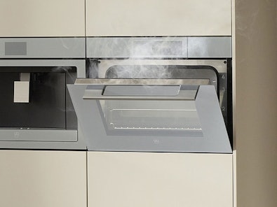 V-ZUG combi-stoomoven geopend met zichtbare stoom en magnetron functionaliteit in moderne keuken