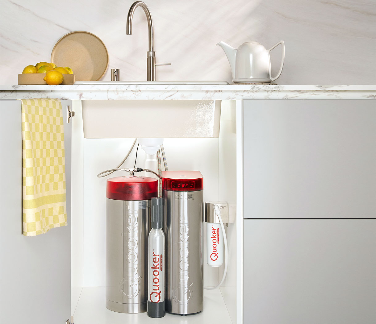 Quooker COMBI reservoir met CUBE geplaatst in een keukenkast onder de spoelbak, aangesloten op een kokendwaterkraan