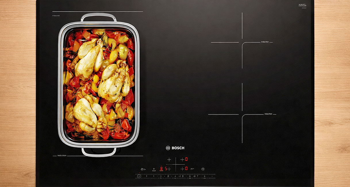 Bosch inductiekookplaat met CombiZone en een braadslede met groenten op het samengevoegde kookoppervlak