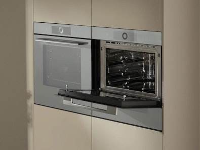 V-ZUG compacte oven geopend met meerdere roosters en bakplaten in ruimtebesparend 45cm design