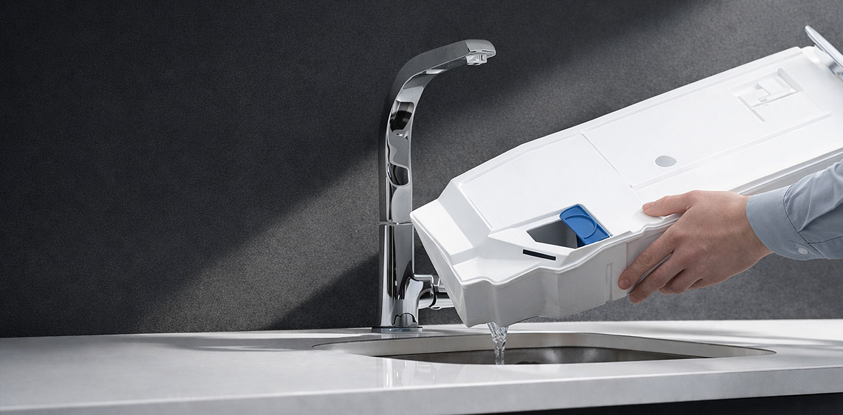 Hand leegt condenswater reservoir van warmtepompdroger boven wasbak geen afvoer naar buiten nodig