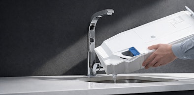 Hand leegt condenswater reservoir van warmtepompdroger boven wasbak geen afvoer naar buiten nodig