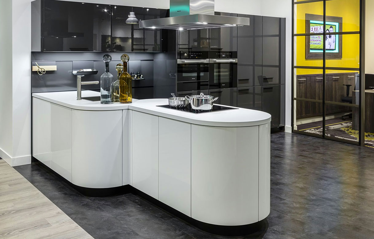 Moderne keuken met schiereiland opstelling, wit kookeiland met afgeronde hoeken en zwarte kastenwand