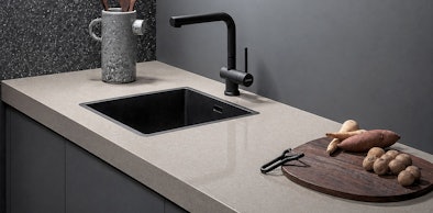 Designkeuken met fenix keukenblad, zwarte spoelbak en houten snijplank met groenten