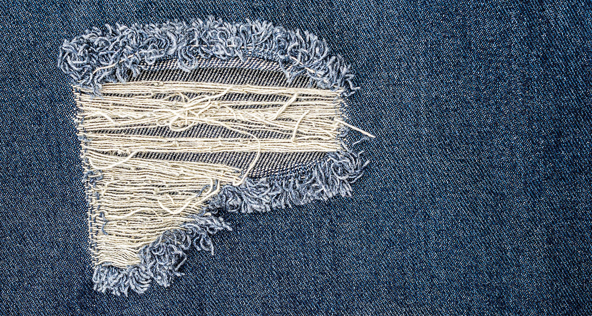 Destroyed jeans met scheuren en losse draden die verder beschadigen in droger
