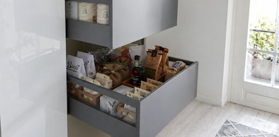 Geopende diepe keukenlade gevuld met voorraad zoals zakken meel, flessen en bakjes