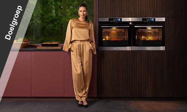 Stijlvolle vrouw in designkeuken met twee AEG SteamBoost-ovens.