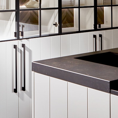 Donker werkblad met strakke rand boven arctiswitte fronten.