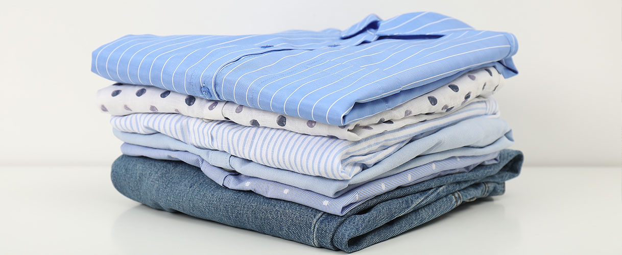 Opgevouwen kledingstukken zoals overhemden, jeans en fijne was voor verschillende droogprogramma’s van een wasdroger