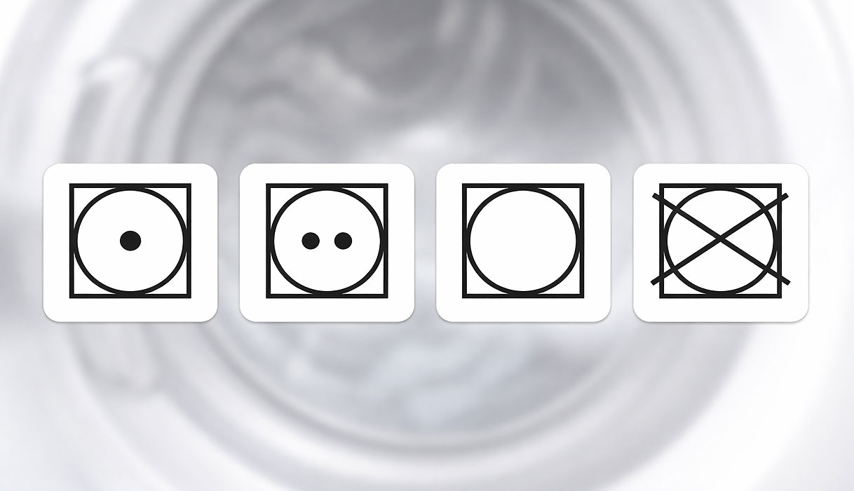 Droogsymbolen op jeans label met uitleg over temperatuur en wel of niet in droger