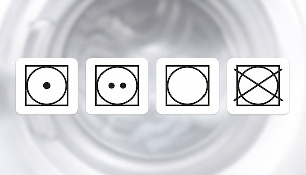 Droogsymbolen op jeans label met uitleg over temperatuur en wel of niet in droger