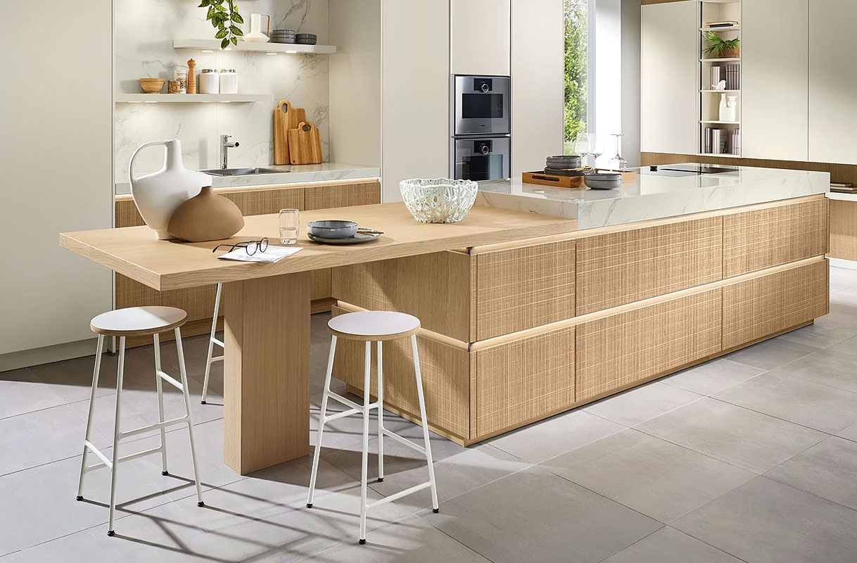 Kookeiland met geïntegreerde eettafel van licht hout, met barkrukken en doorlopend werkblad