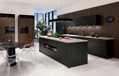 Een exclusieve eilandkeuken met een kookeiland en twee losse hoge kasten.