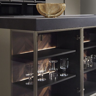 Verlichte eilandvitrines met gerookt glas en visgraat achterwand.