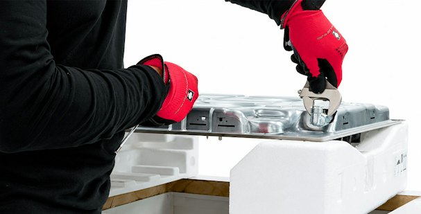 Installateur met handschoenen draait met een sleutel de gasaansluiting van een gaskookplaat vast
