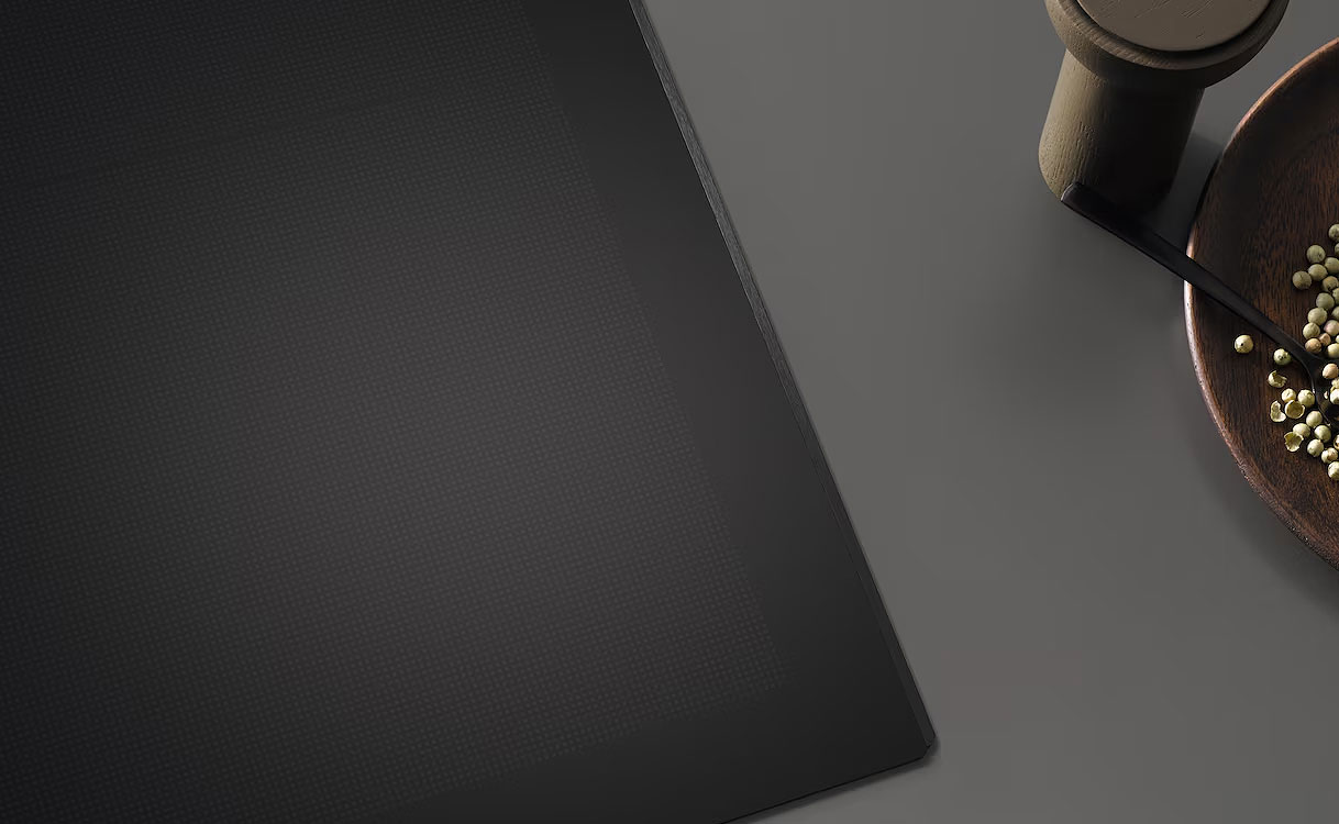 Randloze Miele inductiekookplaat geïntegreerd in donker werkblad met kookpan en ingrediënten