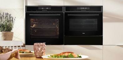 Twee ETNA zwarte inbouw magnetrons naast elkaar in lichte keuken met eettafel en verse maaltijd