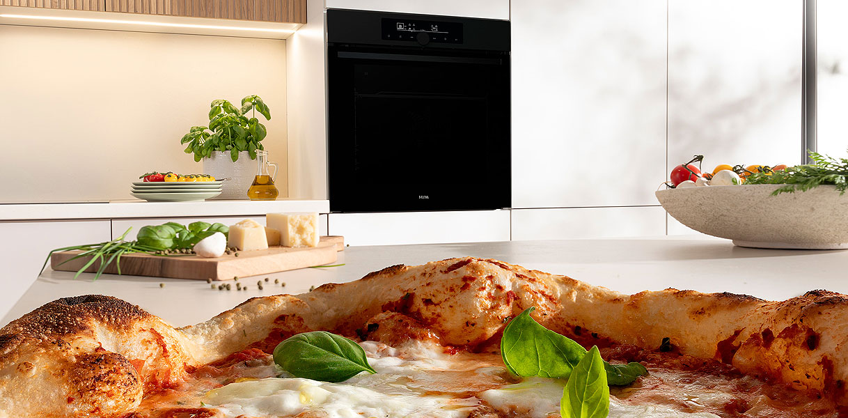 Knapperige pizza met basilicum naast inbouw stoom magnetron met extra functies zoals grill en hetelucht