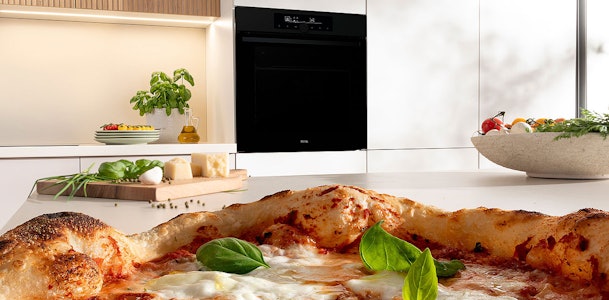 Knapperige pizza met basilicum naast inbouw stoom magnetron met extra functies zoals grill en hetelucht