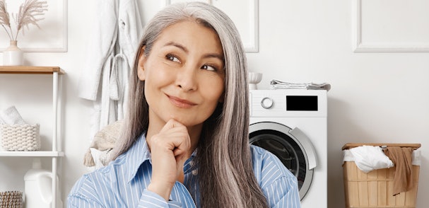 Vrouw denkt na over wasmachine functies in moderne wasruimte