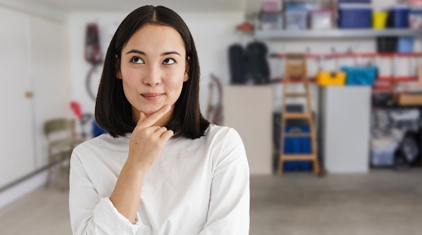 Persoon die nadenkt in een opgeruimde schuur, illustratie bij veelgestelde vragen over koelkasten in de schuur