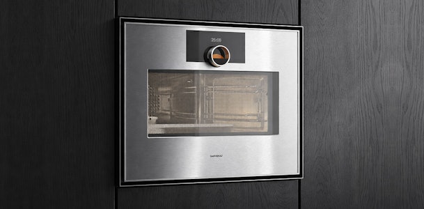Gaggenau Expressive serie combimagnetron in RVS met draaiknop en Soft-Close deur ingebouwd in donkere houten keuken