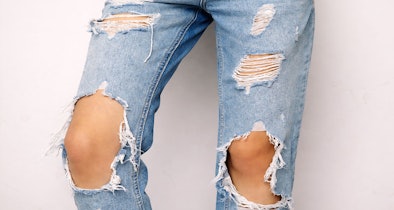 Gescheurde jeans met rafels bij knieën die verder beschadigen door droger