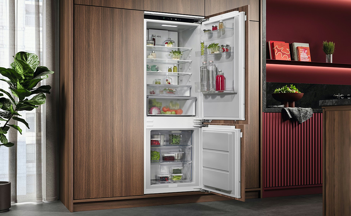 Inbouwkoelkast volledig geïntegreerd in een moderne keuken met geopende koel- en vriesdeuren