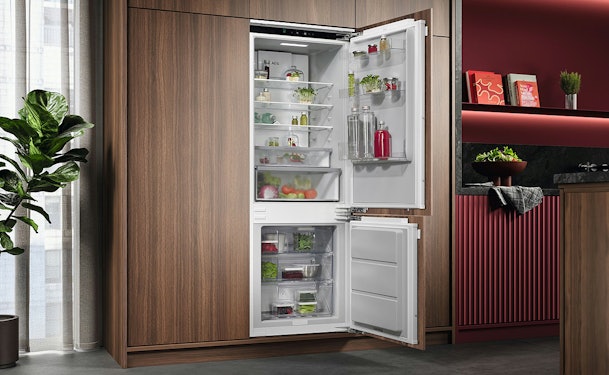Inbouwkoelkast volledig geïntegreerd in een moderne keuken met geopende koel- en vriesdeuren