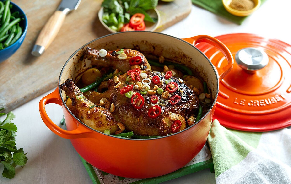 Oranje geëmailleerde gietijzeren braadpan van Le Creuset met kip en groenten