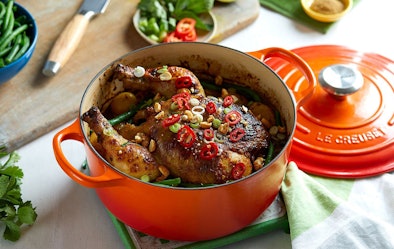 Oranje geëmailleerde gietijzeren braadpan van Le Creuset met kip en groenten