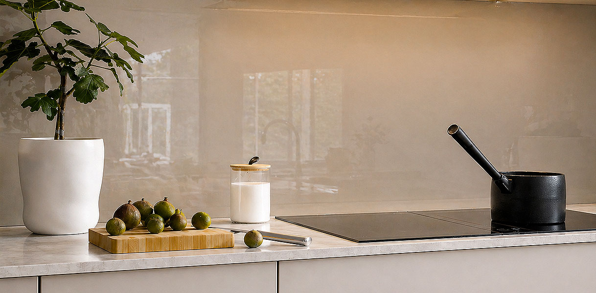 Glazen achterwand in zachte beige tint achter inductiekookplaat in moderne keuken