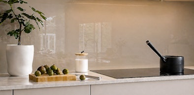 Glazen achterwand in zachte beige tint achter inductiekookplaat in moderne keuken